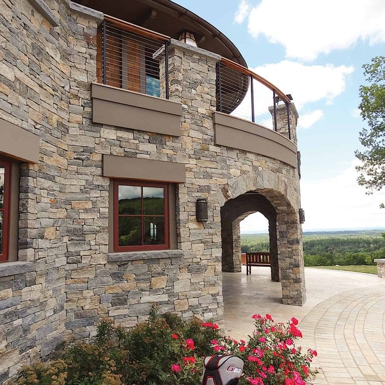 Application image for Boston Blend Granite Veneer - Ledge. The image shows this product being used in a full bed veneer application. The surface finish shown is split-face. Dominant colors shown are gray and tan. The color mix creates a warm feeling.