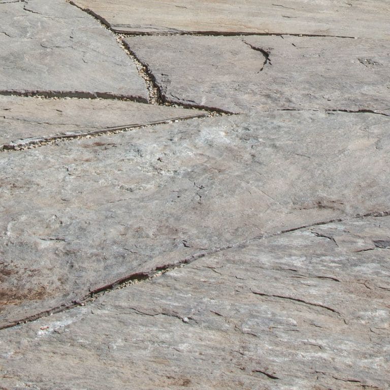 Close-up image for Granite- Mystic Mountain- Natural - Oversized Pavers. The surface finish shown is natural. Dominant colors shown are gray and tan; with beige, blue, purple and white secondaries. Exhibits "movement" and the color mix creates a warm feeling. Random, blotched and streaked color patterns.