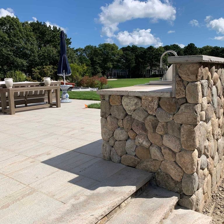 Application image for Boston Blend Granite Veneer - Rounds. The image shows this product being used in a thin veneer application. The surface finish shown is . Dominant colors shown are beige, gray and tan.