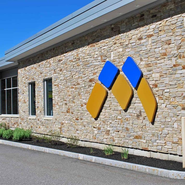 Feature image for New England Tan Granite Veneer - Ledge. The image shows this product being used in a full bed veneer application. The surface finish shown is split-face. Dominant colors shown are beige, gray and tan. The color mix creates a warm feeling.