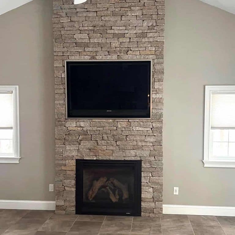 Application image for New England Tan Granite Veneer - Ledge. The image shows this product being used for fireplace surround and thin veneer. The surface finish shown is split-face. Dominant colors shown are gray and tan. The color mix creates a warm feeling.