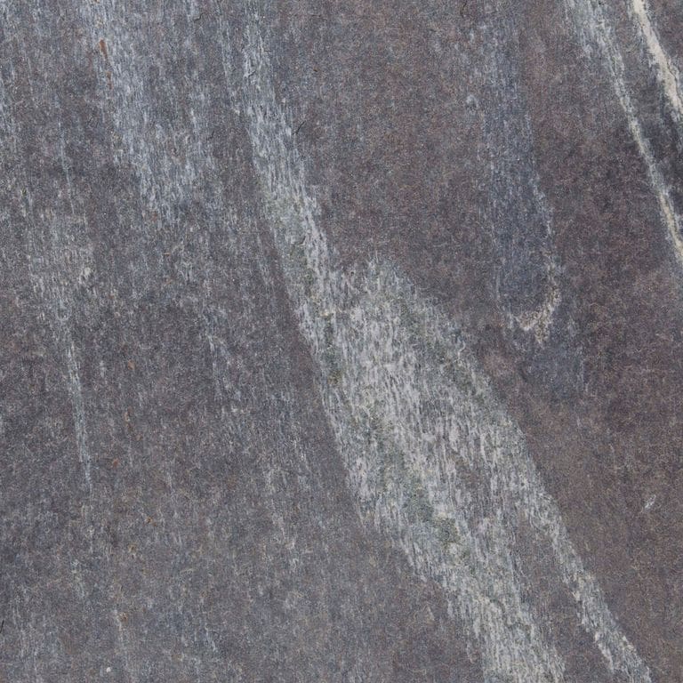 Swatch image cropped for Granite - Mystic Mountain- Dimensional Cut Pavers. The surface finishes shown are flamed and sawn. Dominant colors shown are gray and purple; with blue, brown, green and white secondaries. Exhibits "movement" and the color mix creates a cool feeling. Random, blotched, linear and streaked color patterns.
