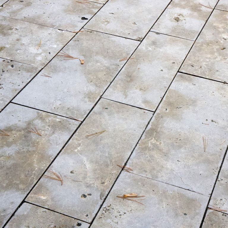 Best close-up image for COPY - Bavarian Dolomite Gray Limestone - Pavers. The image shows this product being used in a driveway pavers application. The surface finish shown is flamed. Dominant colors shown are beige, brown, gray and tan; with orange/rust and cream secondaries. The color mix creates a warm feeling. Regular, blotched and cloudy color patterns. Contains mineral inclusions.