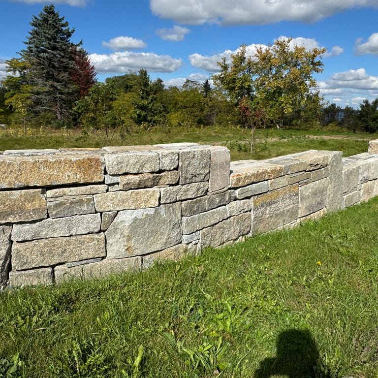 Application image for Test Record - Reclaimed Granite - Wallstone. The image shows this product being used in a landscape wallstone application. The dominant color shown is brown. The color mix creates a warm feeling.