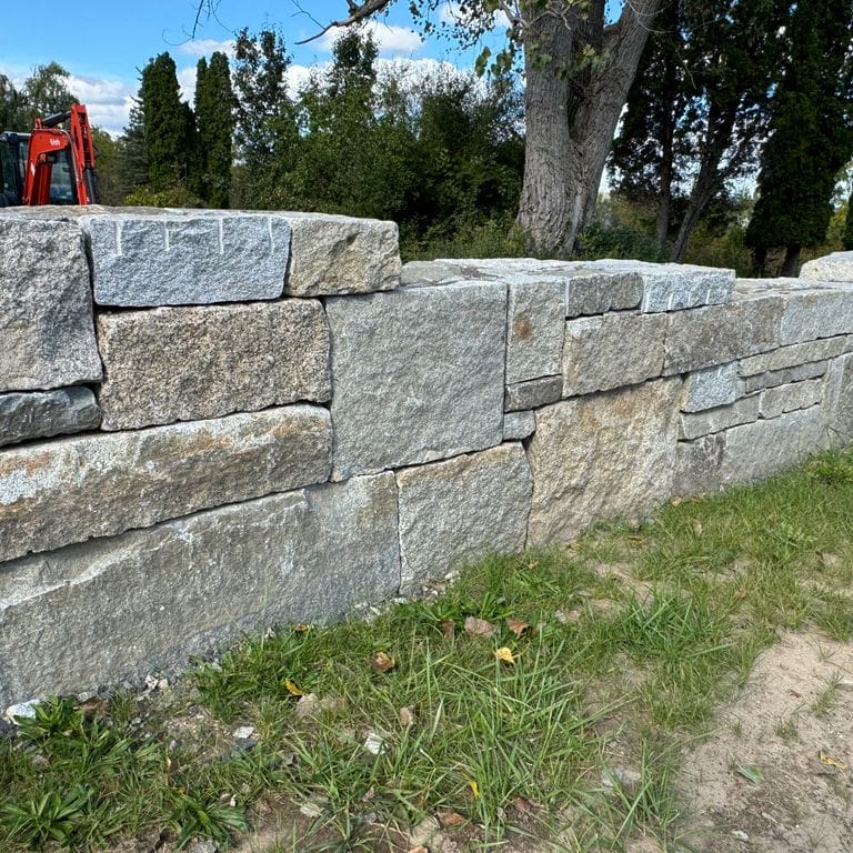Application image for Test Record - Reclaimed Granite - Wallstone. The image shows this product being used in a landscape wallstone application. The dominant color shown is gray.