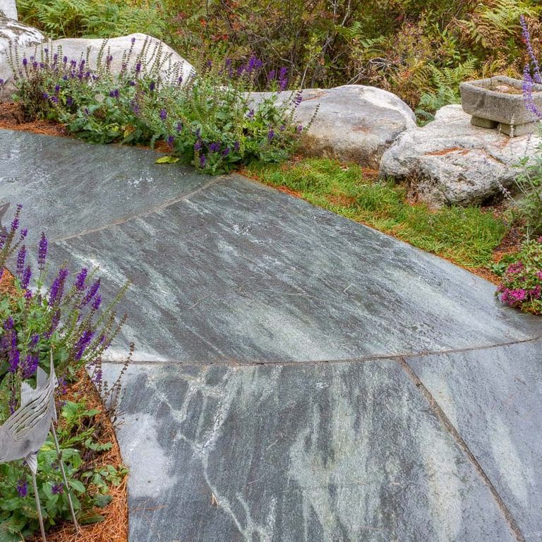 Close-up image for Mystic Mountain Cut to Fit Pavers. The surface finishes shown are flamed and sawn. Dominant colors shown are blue and gray; with green and white secondaries. Exhibits "movement" and the color mix creates a cool feeling. Random, veined, linear and streaked color patterns.