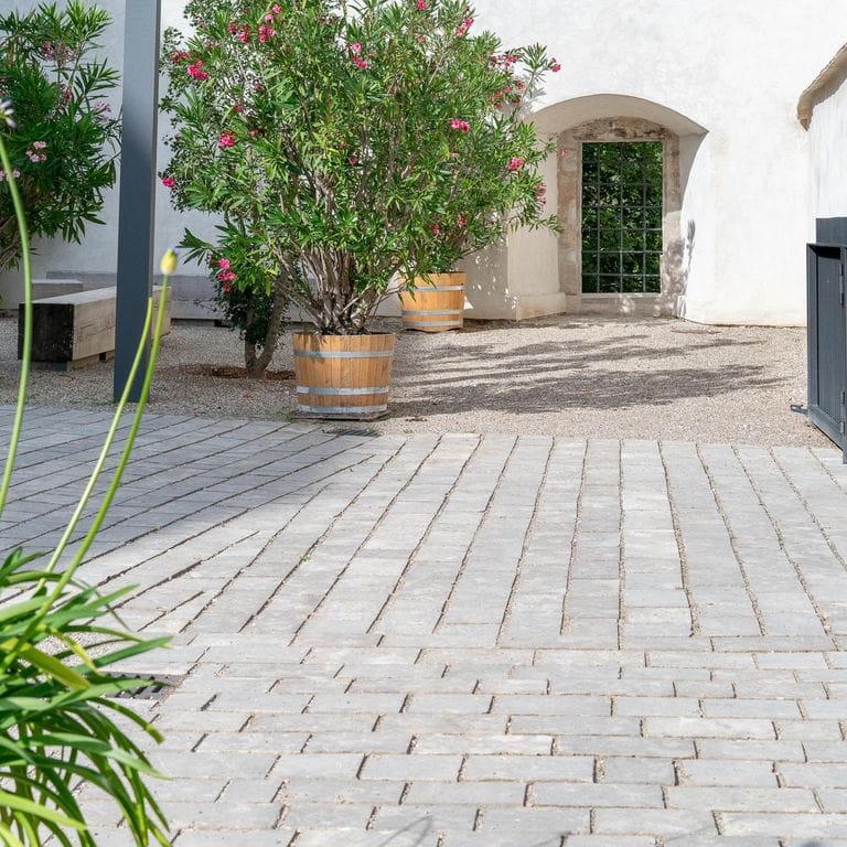 Application image for Bavarian Dolomite Gray Limestone - Sandblasted Cobblestones. The image shows this product being used in a driveway pavers application. The surface finish shown is sand blasted. Dominant colors shown are gray and tan. The color mix creates a warm feeling.