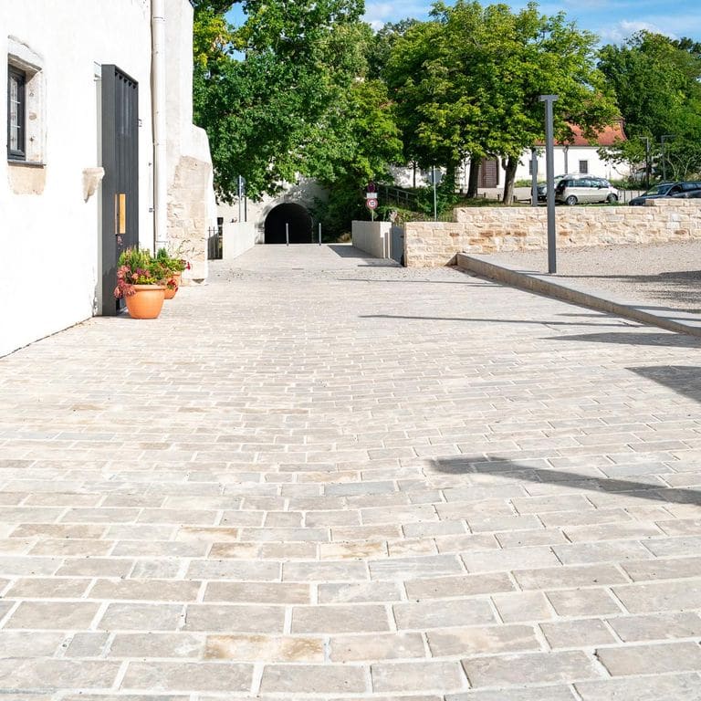 Application image for Bavarian Dolomite Gray Limestone - Sandblasted Cobblestones. The image shows this product being used in a patio pavers application. The surface finish shown is sand blasted. Dominant colors shown are gray and tan.