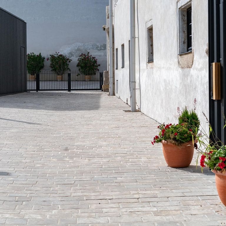 Application image for Bavarian Dolomite Gray Limestone - Sandblasted Cobblestones. The image shows this product being used in a patio pavers application. The surface finish shown is sand blasted. Dominant colors shown are gray and tan. The color mix creates a warm feeling.