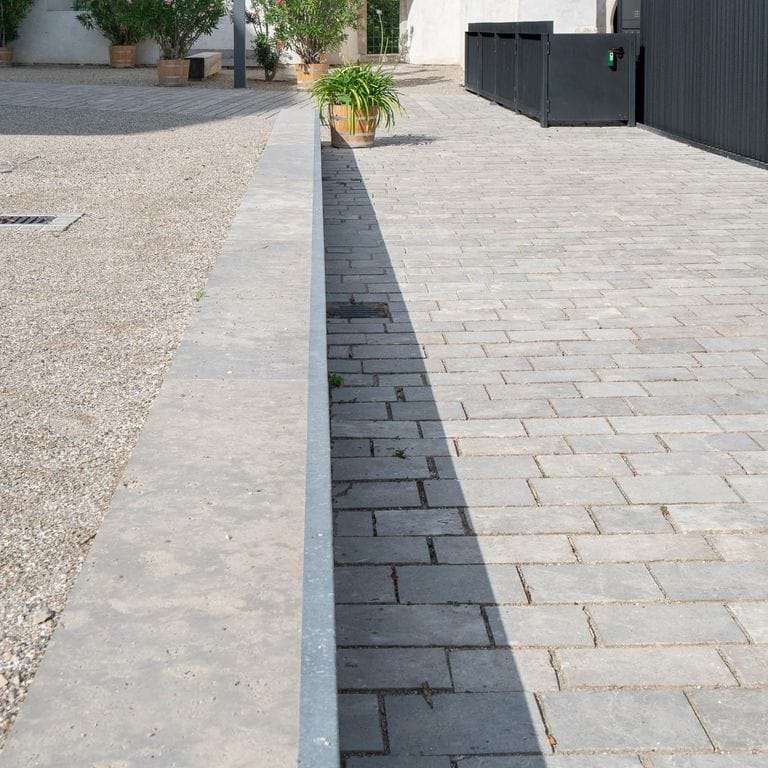 Application image for Bavarian Dolomite Gray Limestone - Sandblasted Cobblestones. The image shows this product being used in a path pavers application. The surface finish shown is sand blasted. The dominant color shown is gray. The color mix creates a warm feeling.