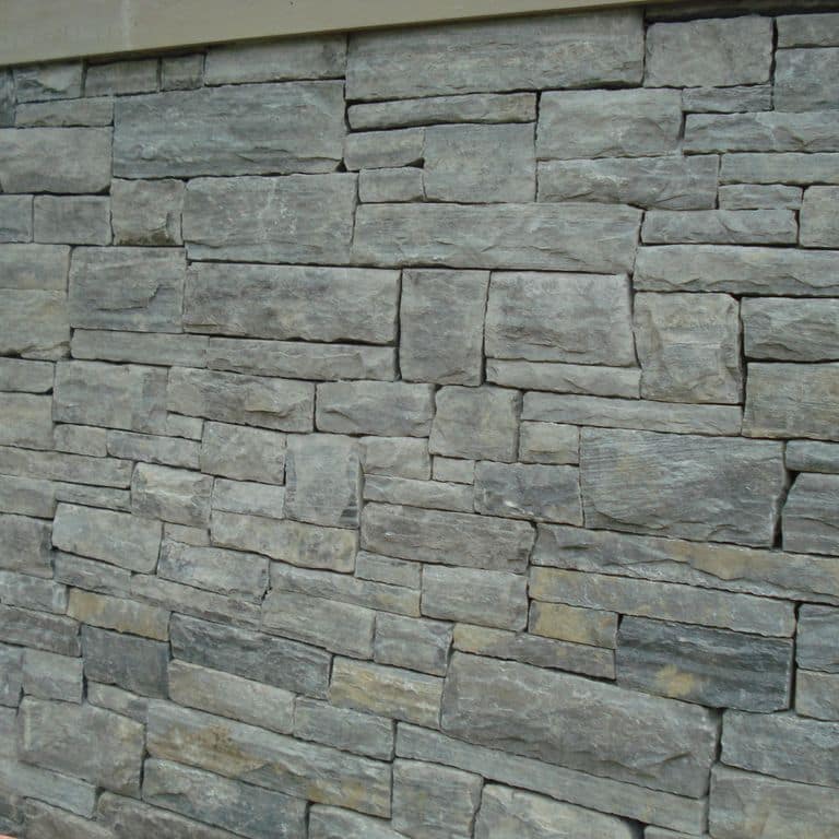 Application image for Granite - Mystic Mountain- Splitface Veneer. The image shows this product being used in a full bed veneer application. Dominant colors shown are green and gray. Exhibits "movement" and the color mix creates a cool feeling. Regular and linear color patterns.