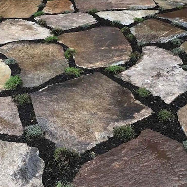 Best close-up image for New England Fieldstone Oversized Pavers. The image shows this product being used in a patio pavers application. The surface finish shown is natural cleft. Dominant colors shown are brown and gray; with a tan secondary. The color mix creates a warm feeling. Regular and streaked color patterns.