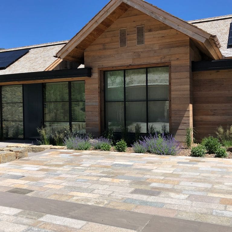 Feature image for Reclaimed Footworn Granite - Plank Pavers. The image shows this product being used for driveway pavers and patio pavers. The surface finish shown is . Dominant colors shown are beige, gray, tan and cream; with beige, pink, purple, white, tan and cream secondaries. Exhibits "movement" and the color mix creates a warm feeling. Speckled, blotched, random and cloudy color patterns.