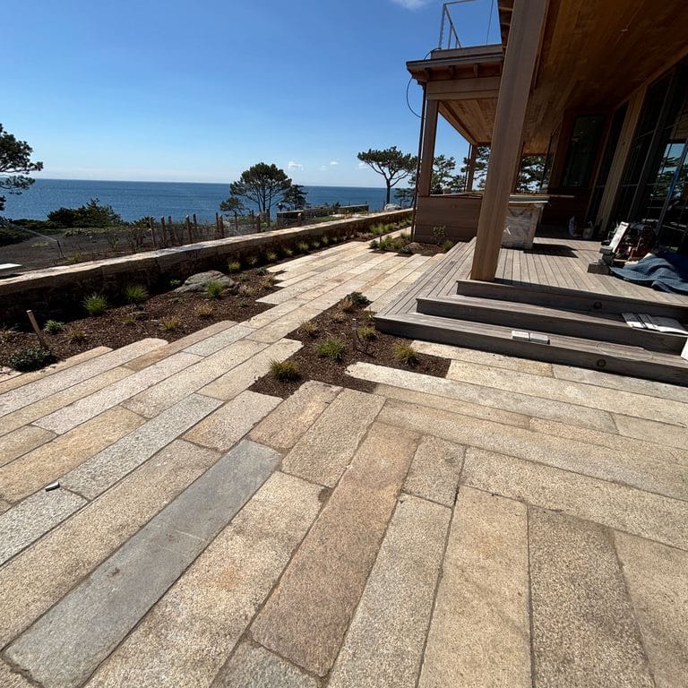 Application image for Reclaimed Footworn Granite - Plank Pavers. The image shows this product being used in a patio pavers application. The surface finish shown is . Dominant colors shown are beige, gray and tan. The color mix creates a warm feeling. Regular and speckled color patterns.