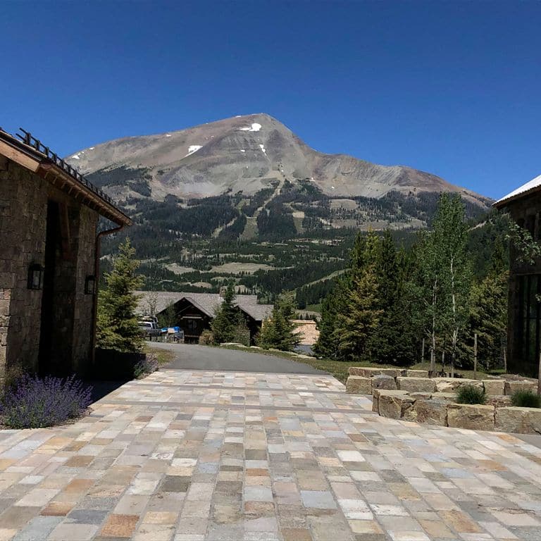 Application image for Reclaimed Footworn Granite - Plank Pavers. The image shows this product being used in a driveway pavers application. The surface finish shown is . Dominant colors shown are gray and tan. The color mix creates a warm feeling. Speckled, blotched, random and cloudy color patterns.