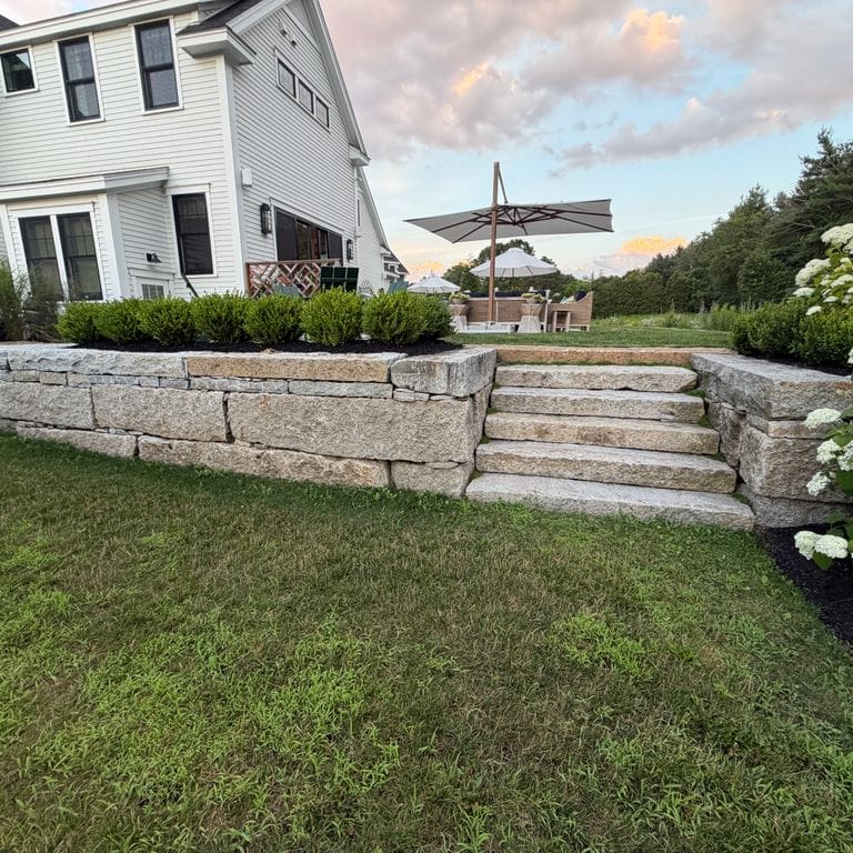 Application image for Reclaimed First Generation Curbstone - Textured Riser and Tread Steps. The image shows this product being used in a monolithic steps application. The surface finish shown is . The dominant color shown is gray; with beige, blue, brown and tan secondaries. The color mix creates a cool feeling. Speckled color pattern.