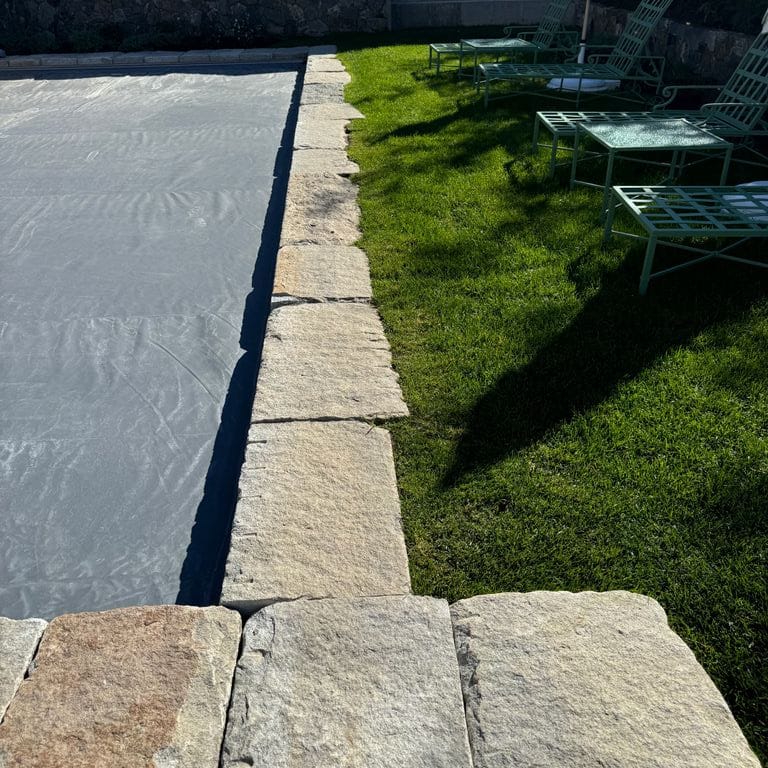 Application image for Granite - Reclaimed Curbstone - Pool Coping. The image shows this product being used in a pool coping application. The surface finish shown is . The dominant color shown is gray. The color mix creates a warm feeling. Regular and random color patterns.