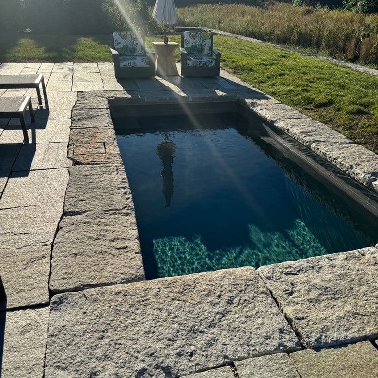 Application image for Granite - Reclaimed Curbstone - Pool Coping. The image shows this product being used in a pool coping application. Dominant colors shown are gray and tan. The color mix creates a cool feeling.