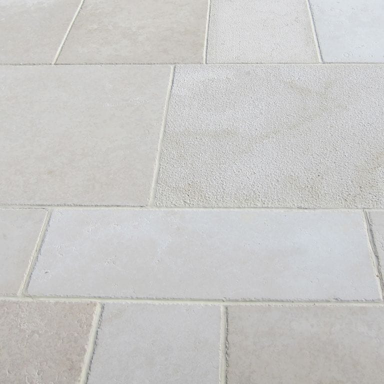 Close-up image for Mountain Hard Limestone Beige - Dimensional Cut Pavers. The surface finishes shown are bush hammered and sand blasted. Dominant colors shown are beige, gray and white; with pink and cream secondaries. The color mix creates a cool feeling. Solid and cloudy color patterns.
