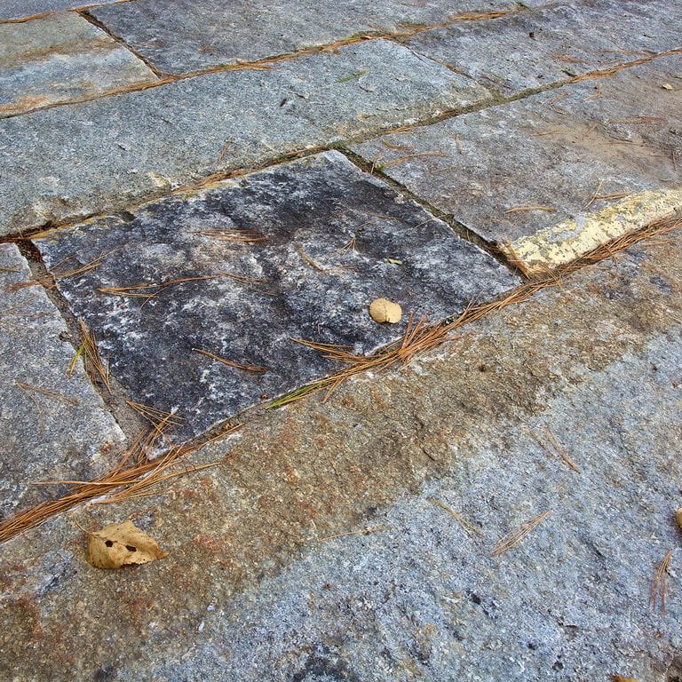 Close-up image for Reclaimed First Generation Granite Curbstone Plank Pavers. The surface finishes shown are weathered and worn. The dominant color shown is gray; with black, blue, brown, green, orange/rust, purple, white, yellow, tan and cream secondaries. Exhibits "movement". Speckled, coarse speckled, blotched and streaked color patterns.