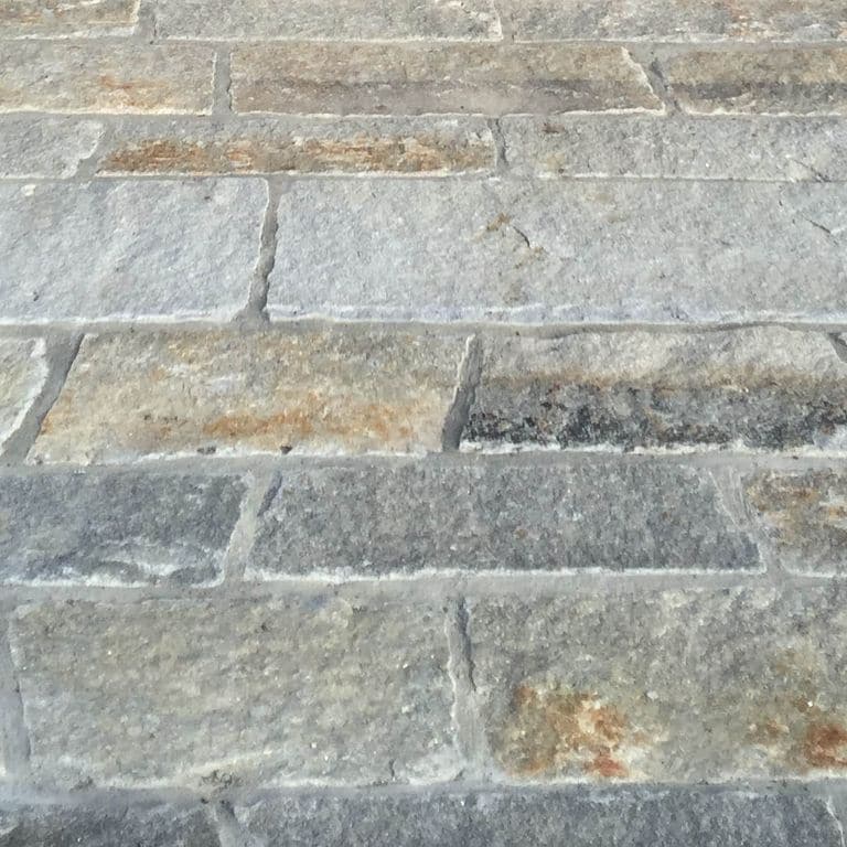 Close-up image for Reclaimed Second Generation Granite Curbstone Plank Pavers. The surface finishes shown are weathered and worn. The dominant color shown is gray; with beige, blue, green, orange/rust, white and tan secondaries. Exhibits "movement" and the color mix creates a warm feeling. Random, speckled and blotched color patterns.