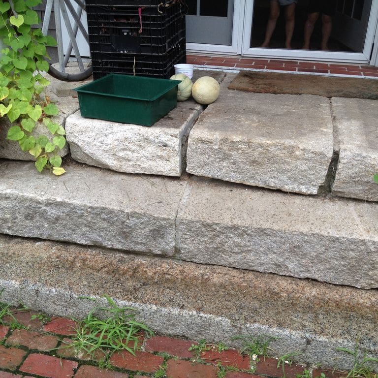 Application image for Reclaimed Second Generation Granite Curbstone Steps - Split Face Riser. The image shows this product being used in a monolithic steps application. This is a landscape stone for outdoor commercial and residential applications. Suitable for general use, freeze-thaw conditions, low heat absorption surfaces, high traffic areas and low slipperiness surfaces situations. Higher to high on the price spectrum.