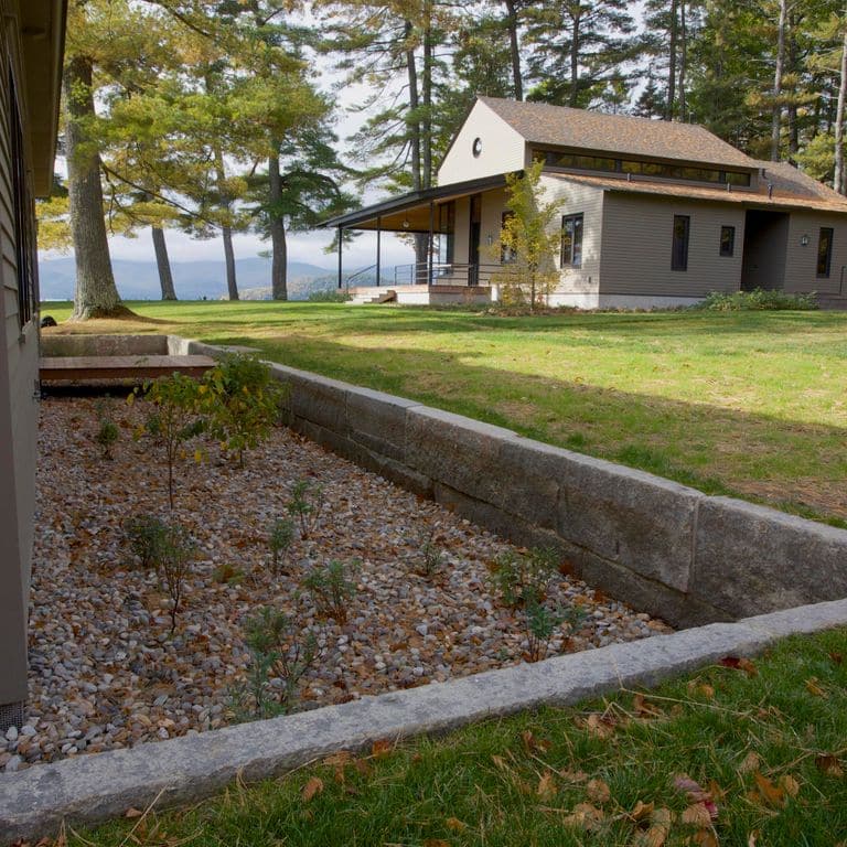 Feature image for Reclaimed First Generation Granite Curbstone Edging. The image shows this product being used in a landscape curbing &amp; edging application. Dominant colors shown are brown and gray. Exhibits "movement". Speckled and blotched color patterns.