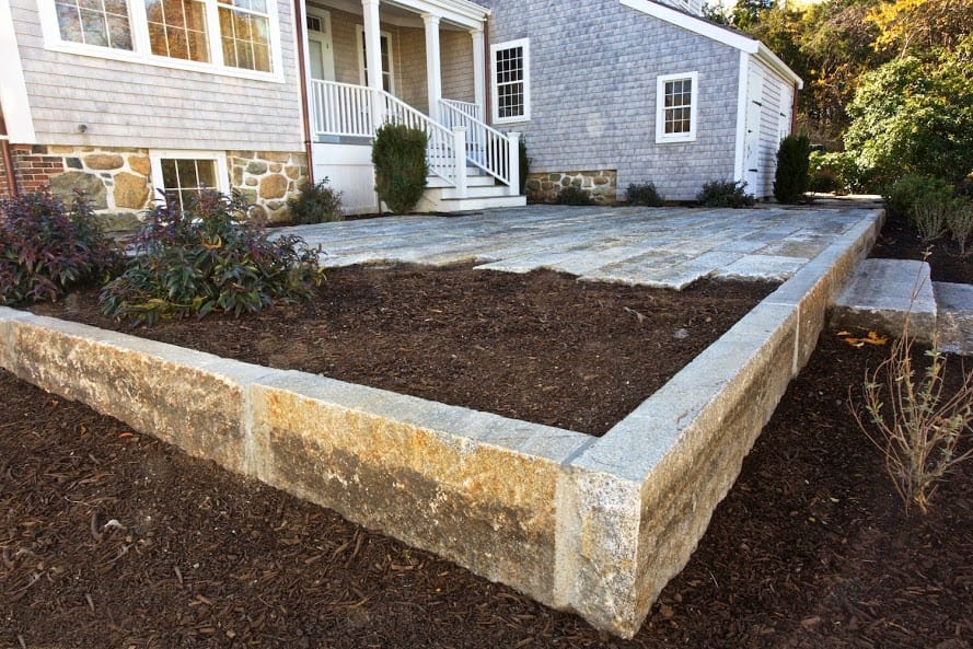 Application image for Reclaimed First Generation Granite Curbstone - Edging. The image shows this product being used in a landscape curbing &amp; edging application. Dominant colors shown are brown and tan. The color mix creates a warm feeling.