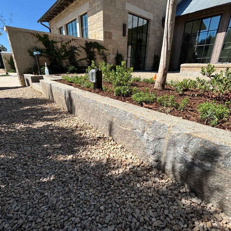 Application image for Reclaimed First Generation Curbstone - Edging. The image shows this product being used in a landscape curbing &amp; edging application. The surface finish shown is . Dominant colors shown are gray and tan. The color mix creates a warm feeling.