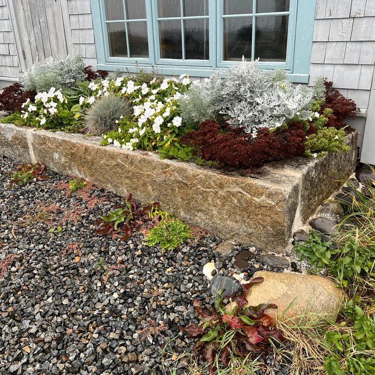 Application image for Reclaimed First Generation Granite Curbstone - Edging. The image shows this product being used in a landscape curbing &amp; edging application. The dominant color shown is brown. The color mix creates a warm feeling.