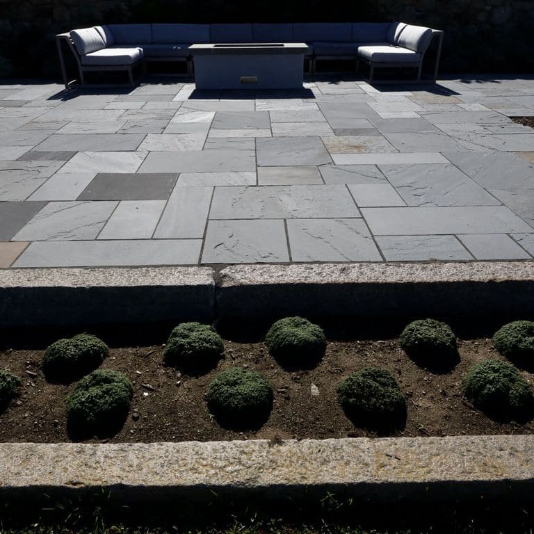 Application image for Reclaimed First Generation Granite Curbstone - Edging. The image shows this product being used in a landscape curbing &amp; edging application. The surface finish shown is a combination of weathered and worn. The dominant color shown is brown; with a gray secondary.