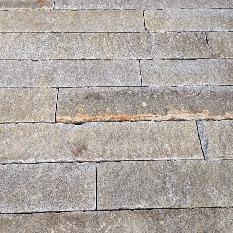 Close-up image for Reclaimed Granite Curbstone - Junior Plank Pavers. The surface finishes shown are weathered and worn. Dominant colors shown are beige and gray; with brown, orange/rust, pink, purple, white, tan and cream secondaries. Exhibits "movement" and the color mix creates a warm feeling. Speckled and blotched color patterns.