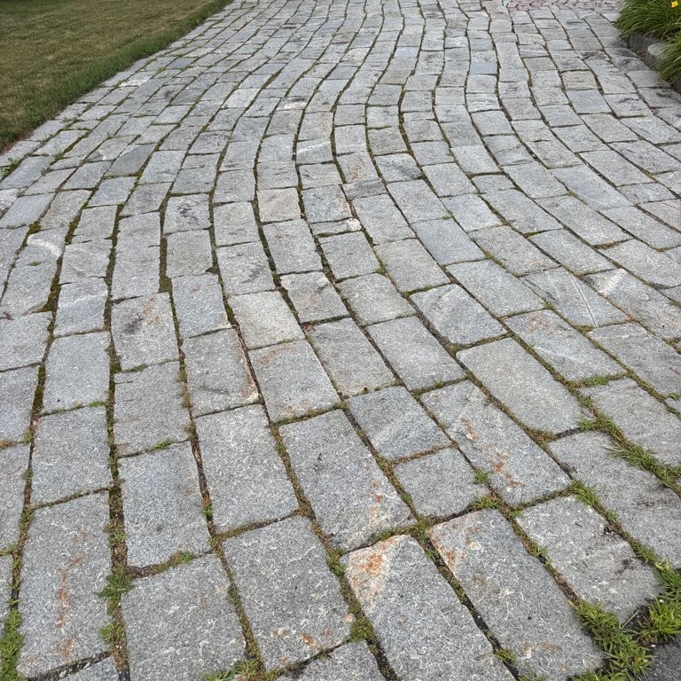 Application image for Reclaimed Granite Curbstone - Junior Plank Pavers. The image shows this product being used in a driveway pavers application. The surface finish shown is . The dominant color shown is gray. The color mix creates a warm feeling.