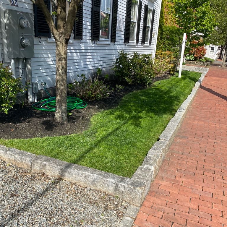Application image for Reclaimed Granite Curbstone - Junior Edging. The image shows this product being used in a landscape curbing &amp; edging application. This is a landscape stone for outdoor commercial and residential applications. Suitable for general use, freeze-thaw conditions, low heat absorption surfaces, high traffic areas, low slipperiness surfaces and high heel compatibilty situations. Moderate to higher on the price spectrum.