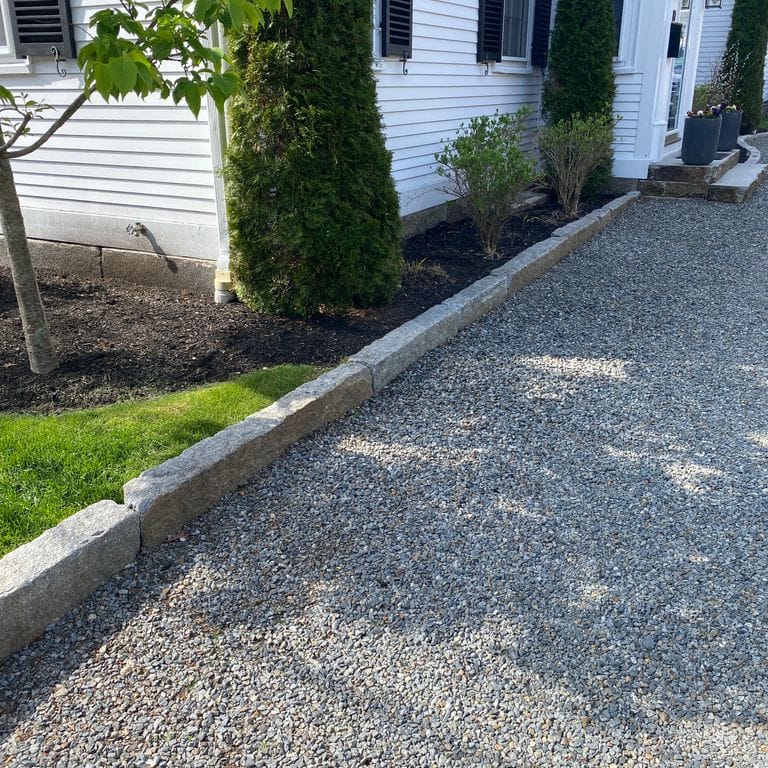 Application image for Reclaimed Granite Curbstone - Junior Edging. The image shows this product being used in a landscape curbing &amp; edging application. This is a landscape stone for outdoor commercial and residential applications. Suitable for general use, freeze-thaw conditions, low heat absorption surfaces, high traffic areas, low slipperiness surfaces and high heel compatibilty situations. Moderate to higher on the price spectrum.