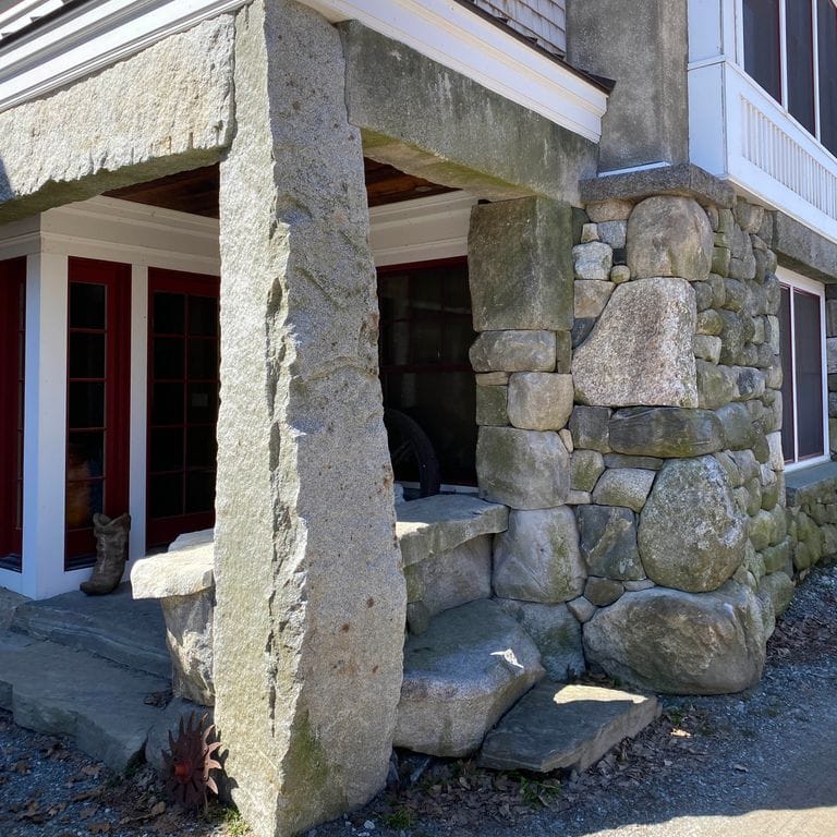 Close-up image for Reclaimed Granite Columns. The surface finishes shown are split-face and weathered. The dominant color shown is gray; with beige, green, white and cream secondaries. Exhibits "movement" and the color mix creates a cool feeling. Speckled color pattern.