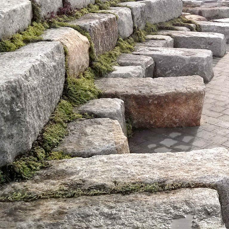 Close-up image for Granite - Reclaimed Block - Benches. The surface finishes shown are weathered and worn. The dominant color shown is gray; with beige, black, brown, orange/rust, pink, purple, white, tan and cream secondaries. Random, speckled, coarse speckled and blotched color patterns.