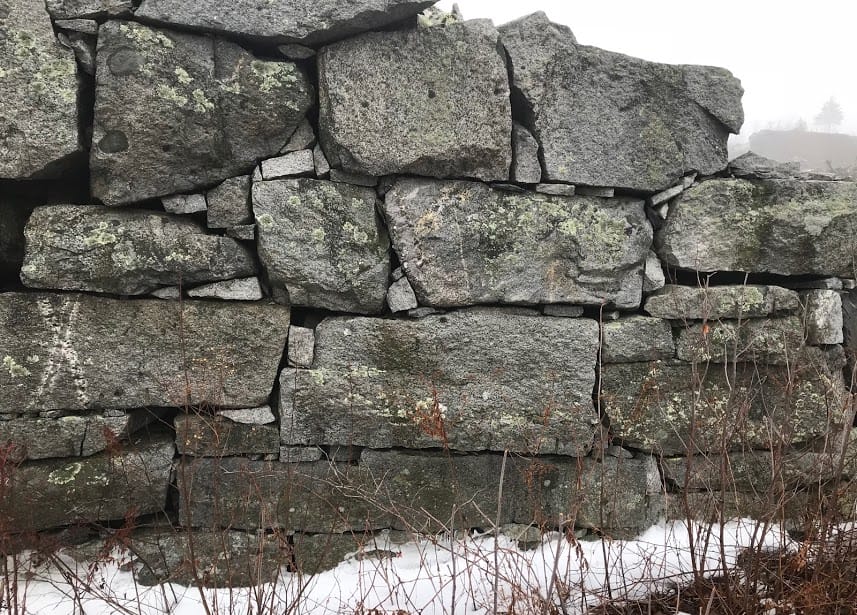 Application image for Granite - Reclaimed New England Quarry Tailings - Oversized Wallstone. The image shows this product being used in a landscape wallstone application. The dominant color shown is gray. The color mix creates a cool feeling.