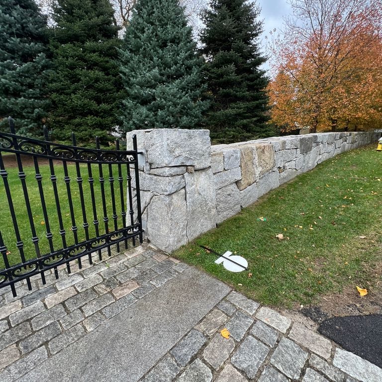 Application image for Granite - Reclaimed New England Quarry Tailings - Oversized Wallstone. The image shows this product being used in a landscape wallstone application. The dominant color shown is gray. The color mix creates a cool feeling.