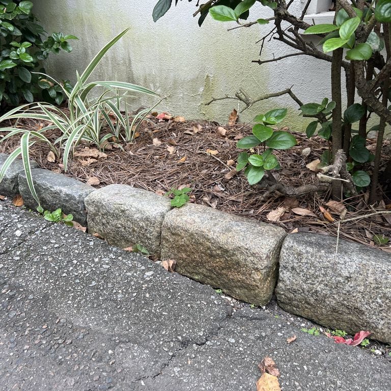 Application image for Granite - Reclaimed New England Cobblestones - Jumbo Edging. The image shows this product being used in a landscape curbing &amp; edging application. The surface finish shown is . The dominant color shown is gray. The color mix creates a warm feeling.