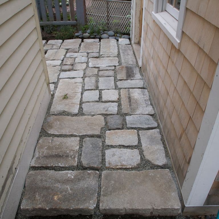 Application image for Granite - Reclaimed New England Cobblestones - Super Jumbo Pavers. The image shows this product being used in a path pavers application. The dominant color shown is gray. The color mix creates a cool feeling.