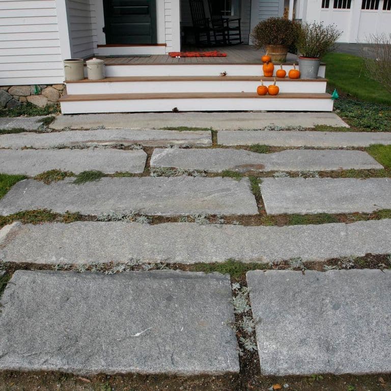 Application image for Reclaimed Granite Foundation Stone - Pavers. The image shows this product being used in a path pavers application. The surface finish shown is . The dominant color shown is gray. The color mix creates a warm feeling.