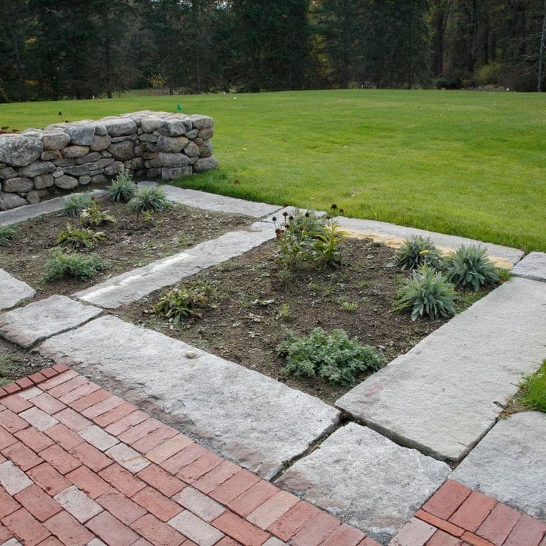 Application image for Reclaimed Granite Foundation Stone - Pavers. The image shows this product being used in a landscape curbing &amp; edging application. The surface finish shown is . The dominant color shown is gray.