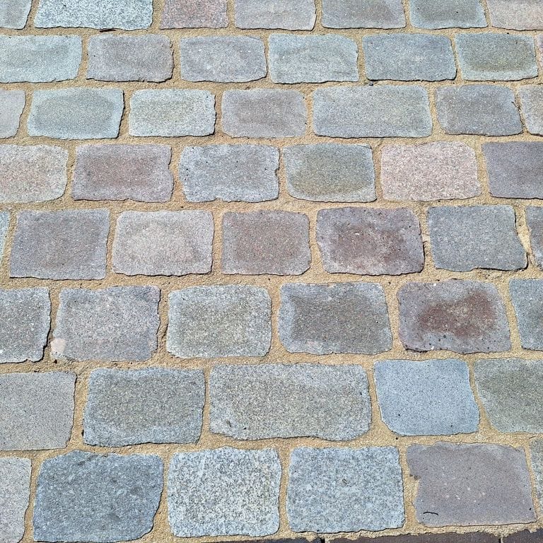 Best close-up image for Reclaimed Swedish Granite Cobblestones - Flat Surface. The surface finish shown is sawn. The dominant color shown is gray; with beige, blue, brown, green, orange/rust, purple, white and tan secondaries. The color mix creates a warm feeling. Fine speckled, speckled and random color patterns.