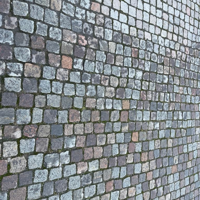 Application image for Reclaimed Swedish Granite Cobblestones - Worn Surface. The image shows this product being used in a public area application. The surface finish shown is . The dominant color shown is gray. The color mix creates a cool feeling.