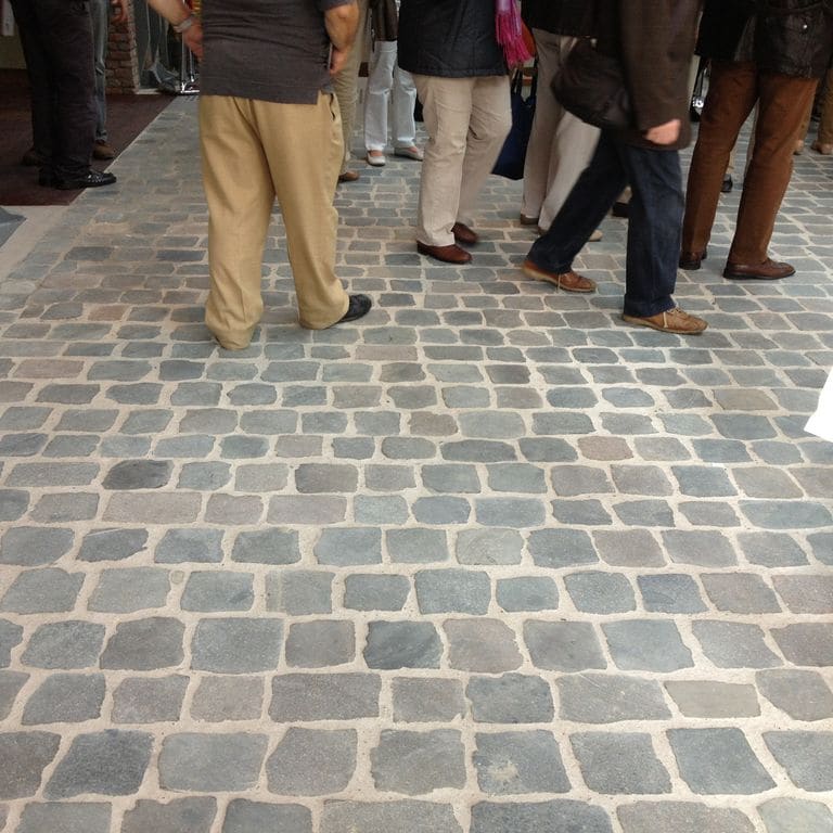 Application image for Porphyry - Reclaimed European Cobblestone - Square - Flat Surface. The image shows this product being used in an interior floor application. The surface finish shown is sawn. The dominant color shown is gray. The color mix creates a warm feeling.