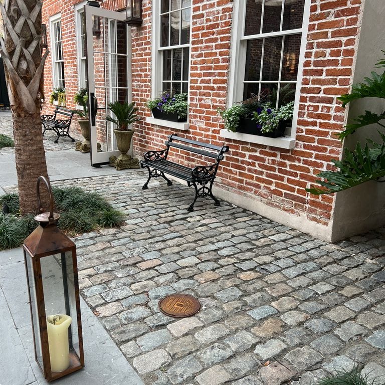 Application image for Reclaimed European Porphyry Cobblestones - Rectangle - Worn. The image shows this product being used in a path pavers application. The surface finish shown is . Dominant colors shown are black, brown and gray. The color mix creates a warm feeling.