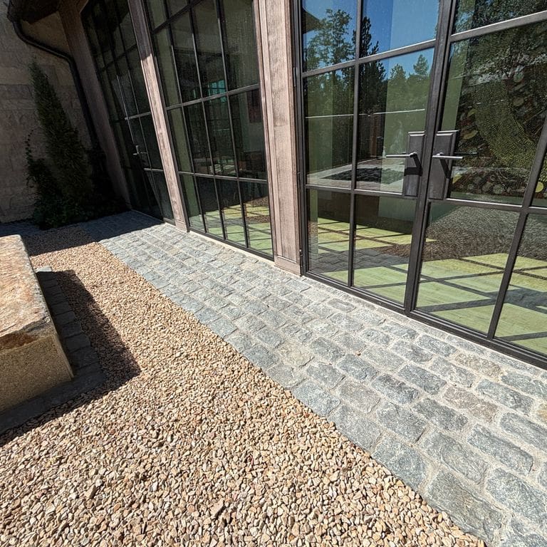 Application image for Reclaimed European Porphyry Cobblestones - Rectangle - Worn Surface. The image shows this product being used in a patio pavers application. The surface finish shown is . Dominant colors shown are beige and gray. The color mix creates a warm feeling.