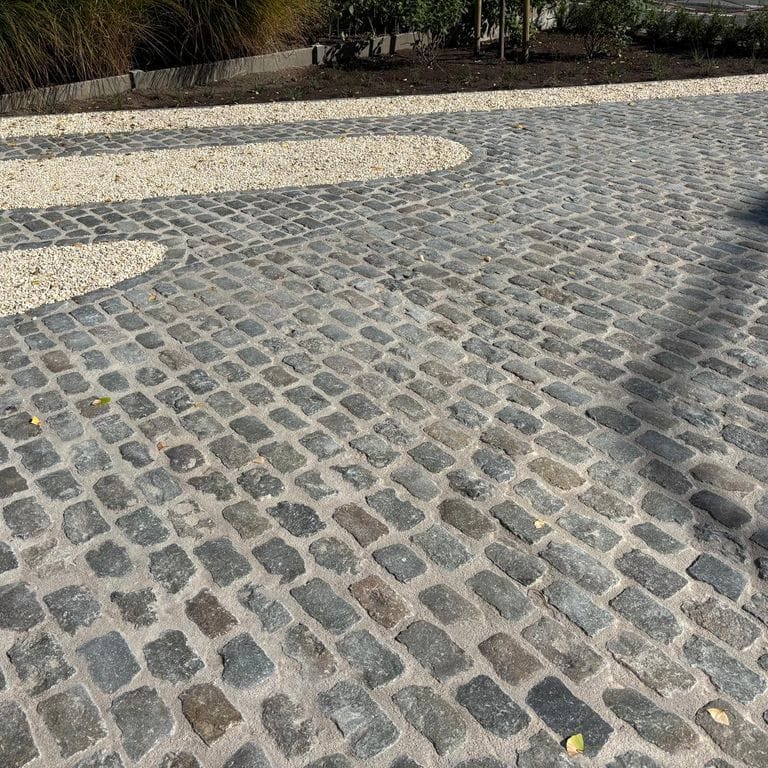 Application image for Reclaimed European Porphyry Cobblestones - Rectangle - Worn Surface. The image shows this product being used in a driveway pavers application. The surface finish shown is . The dominant color shown is gray.