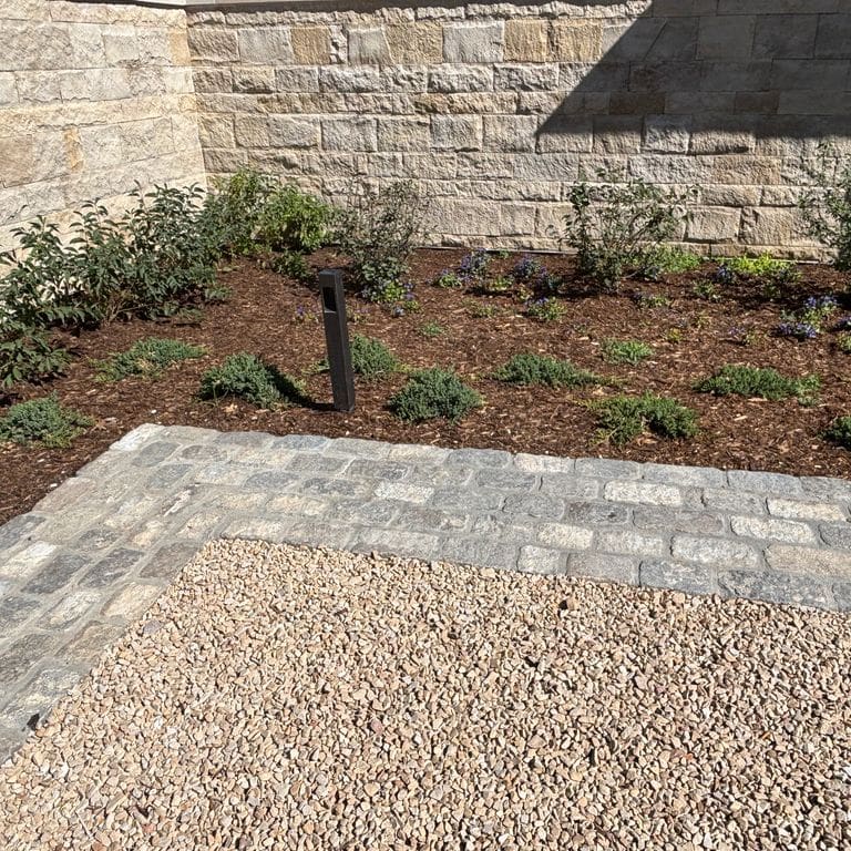 Application image for Reclaimed European Porphyry Cobblestones - Rectangle - Worn Surface. The image shows this product being used in a landscape curbing &amp; edging application. The surface finish shown is . The dominant color shown is gray. The color mix creates a warm feeling.